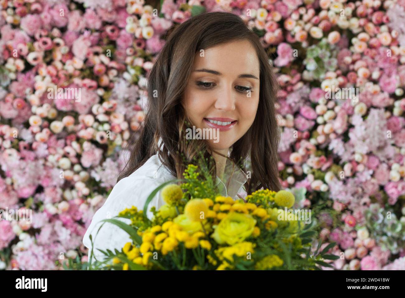 Wunderschöne gesunde Frau lächelt und hält bunte gelbe Farbe Blumenstrauß auf floralem Frühling oder Sommer Hintergrund, Studio Mode Schönheit Porträt Stockfoto