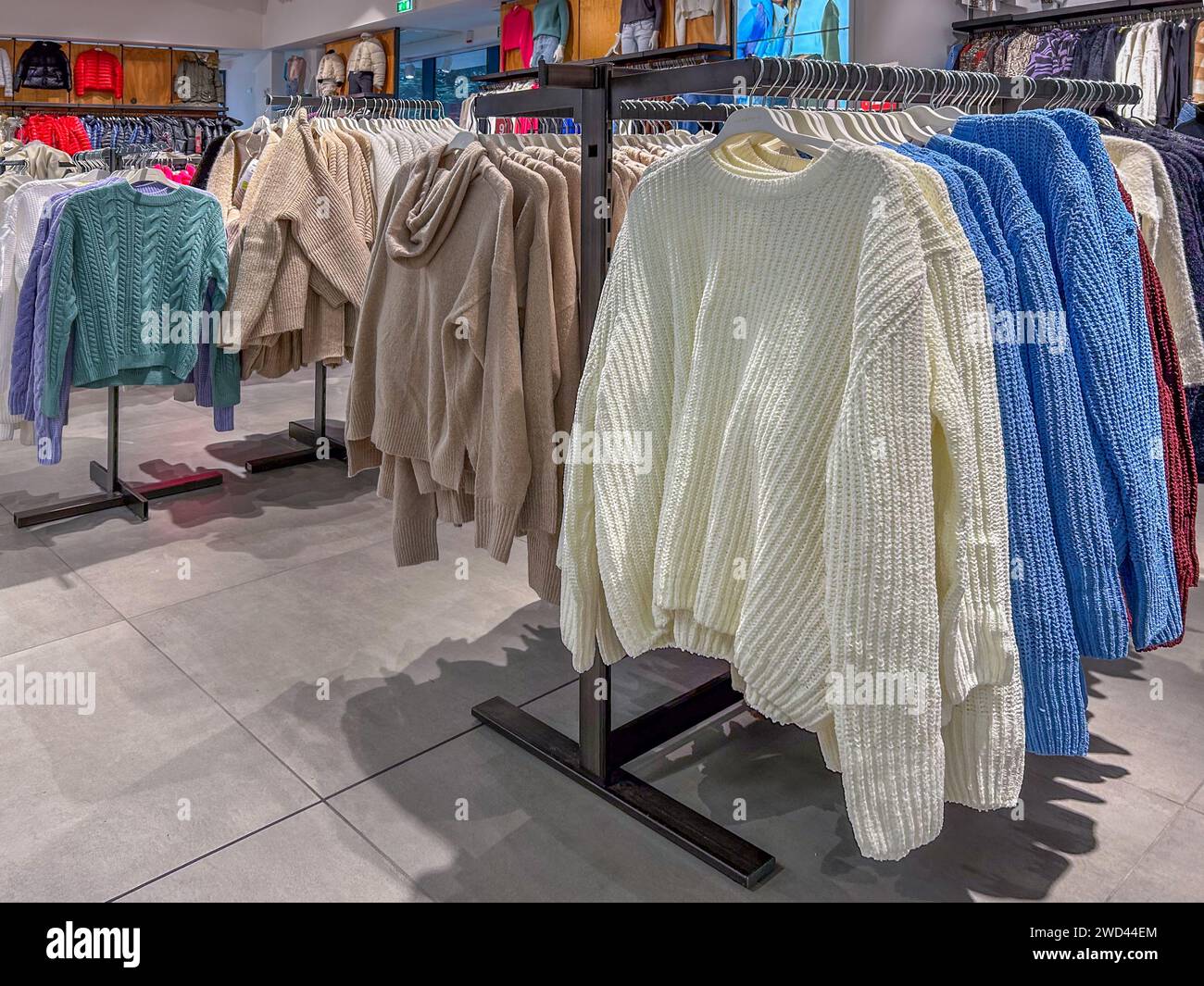 Pullover und Pullover für Frauen in verschiedenen Formen und Farben auf der Wäscheleine im Bekleidungsgeschäft Stockfoto
