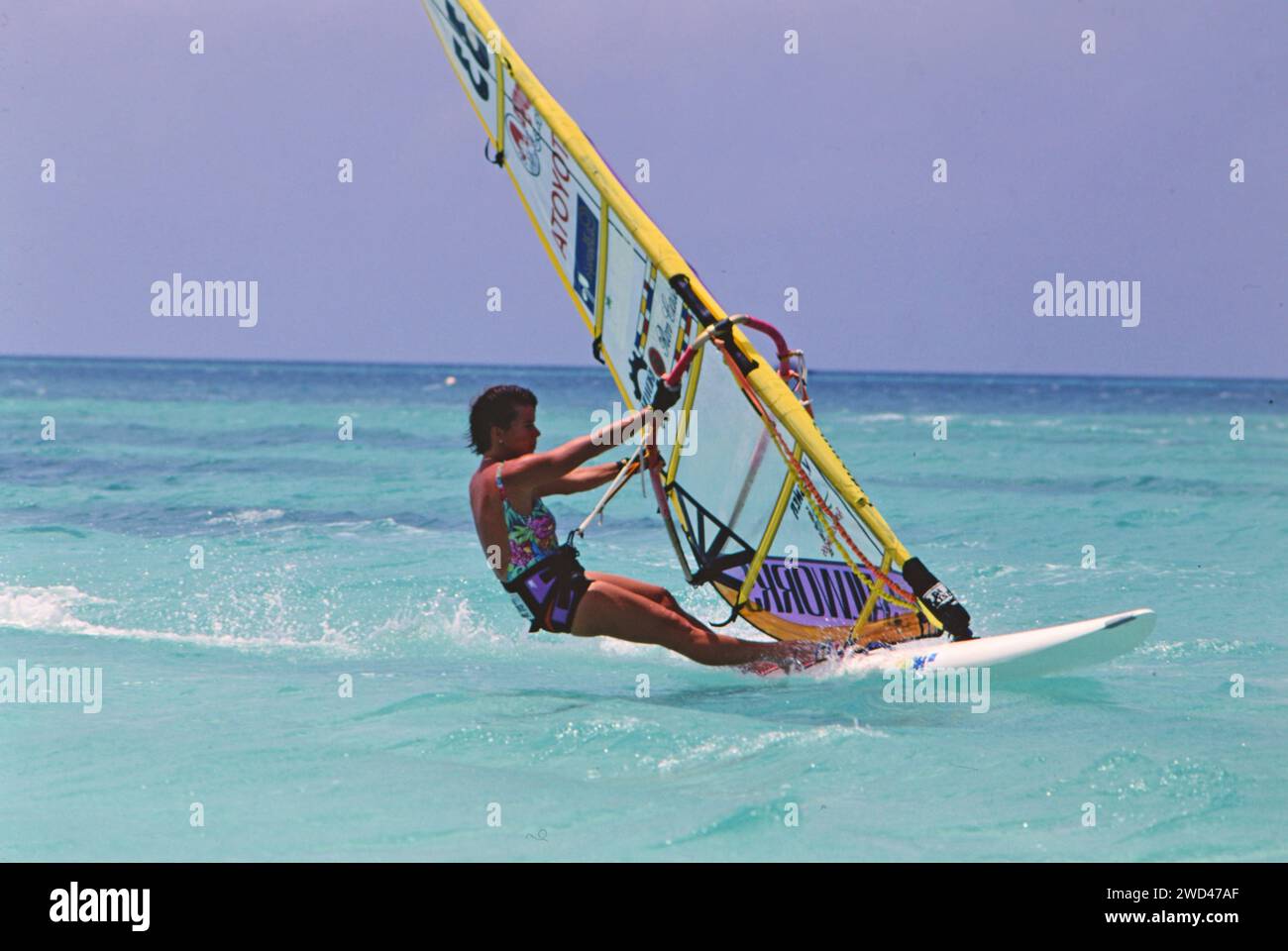 Junger Mann Windsurfen (Boardsegeln) im blauen Wasser vor Aruba CA. Anfang der 1990er Jahre Bitte schreiben Sie dem Fotografen Joan Iaconetti zu Stockfoto