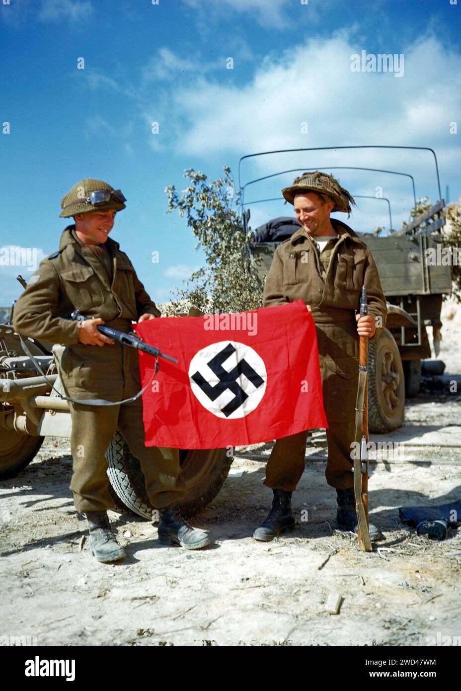 IN DER NÄHE VON HAUT MESNIL, FRANKREICH - 10. August 1944 - zwei Soldaten der kanadischen Armee hissen eine Nazi-Flagge, die sie in einem Steinbruch südlich von Hautmesnil, Frankreich, gefangen nahmen. Stockfoto