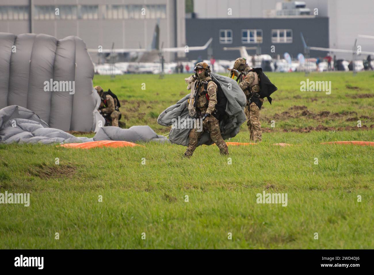 Polnische Spezialkräfte (JW AGAT) landen Fallschirmjäger mit Fallschirmen auf einem europäischen Flugplatz, nachdem sie einen HALO-Sprung von einem Hubschrauber in den Himmel durchgeführt hatten. Stockfoto