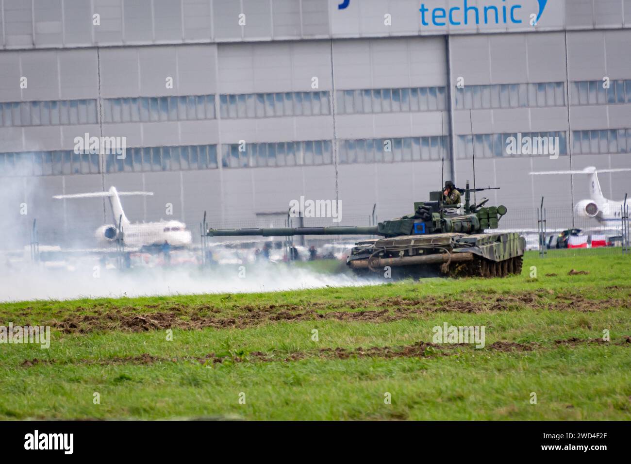 T72 Tank (M4 CZ Variantennummer 029) fährt während einer Demonstrationsübung auf einem schlammigen Feld vor NATO- und Tschechischen Flaggen. Stockfoto