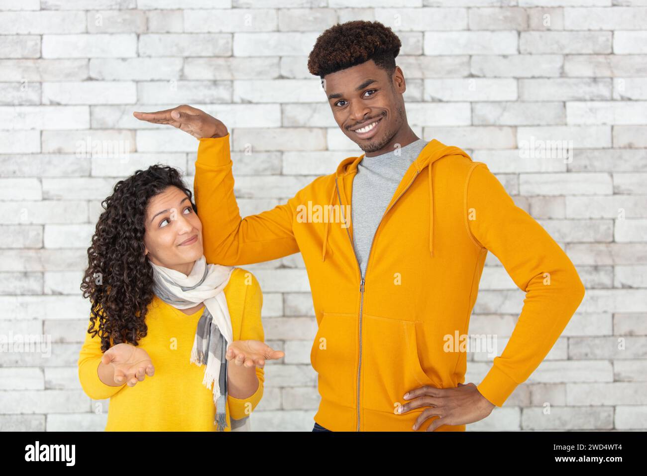 Großer Mann, der die Größe einer kleinen Frau misst Stockfoto