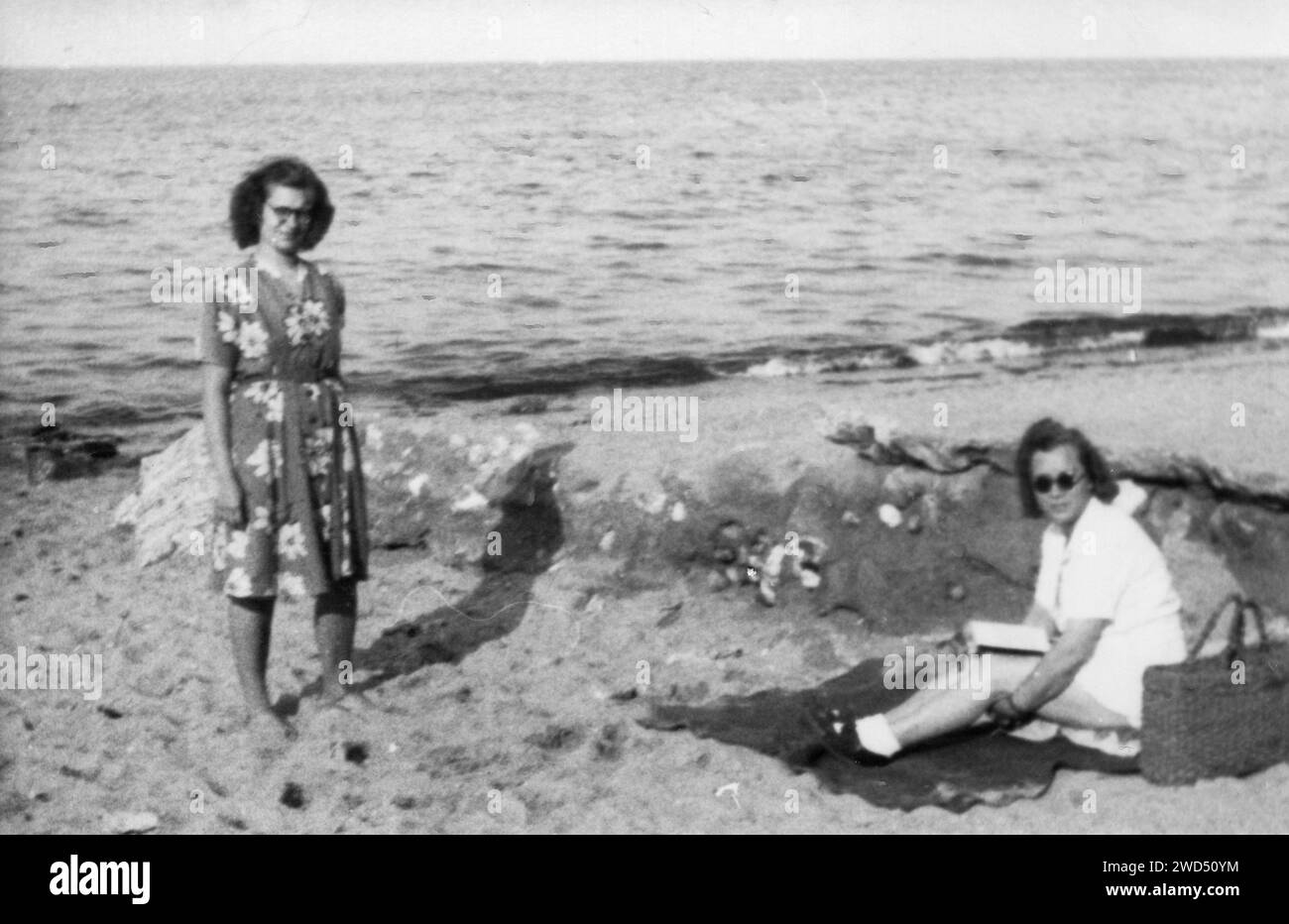 Ein antikes Foto zeigt zwei kaukasische Frauen am Strand am Meer. Deutschland. Datum unbekannt, um die 1950er Jahre Stockfoto