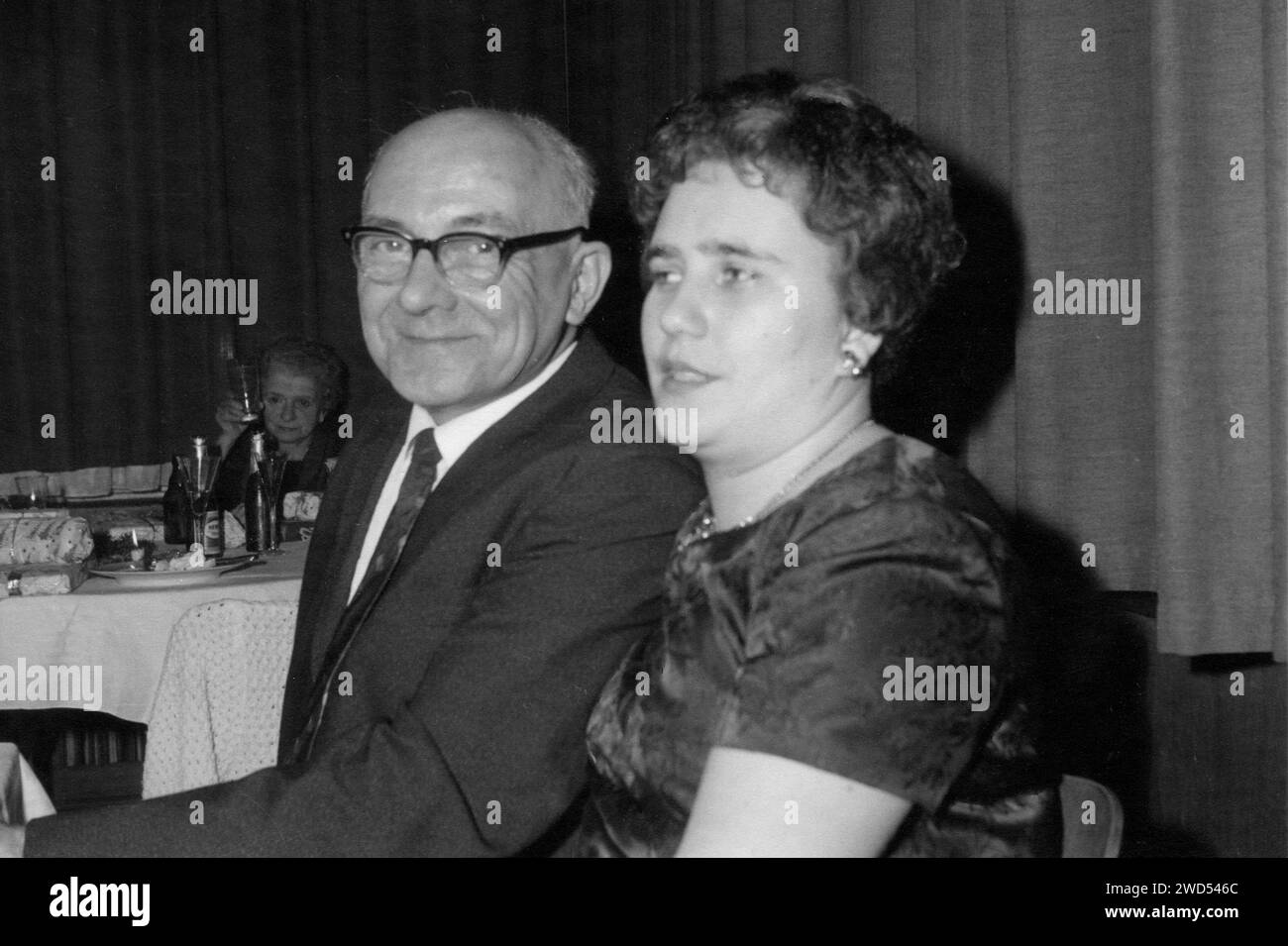 Ein antikes Foto zeigt einen älteren Glatzkopf in Brille und einem Business-Anzug mit Krawatte sitzt mit einer jungen Frau auf einer Party. Deutschland. Datum unbekannt Stockfoto