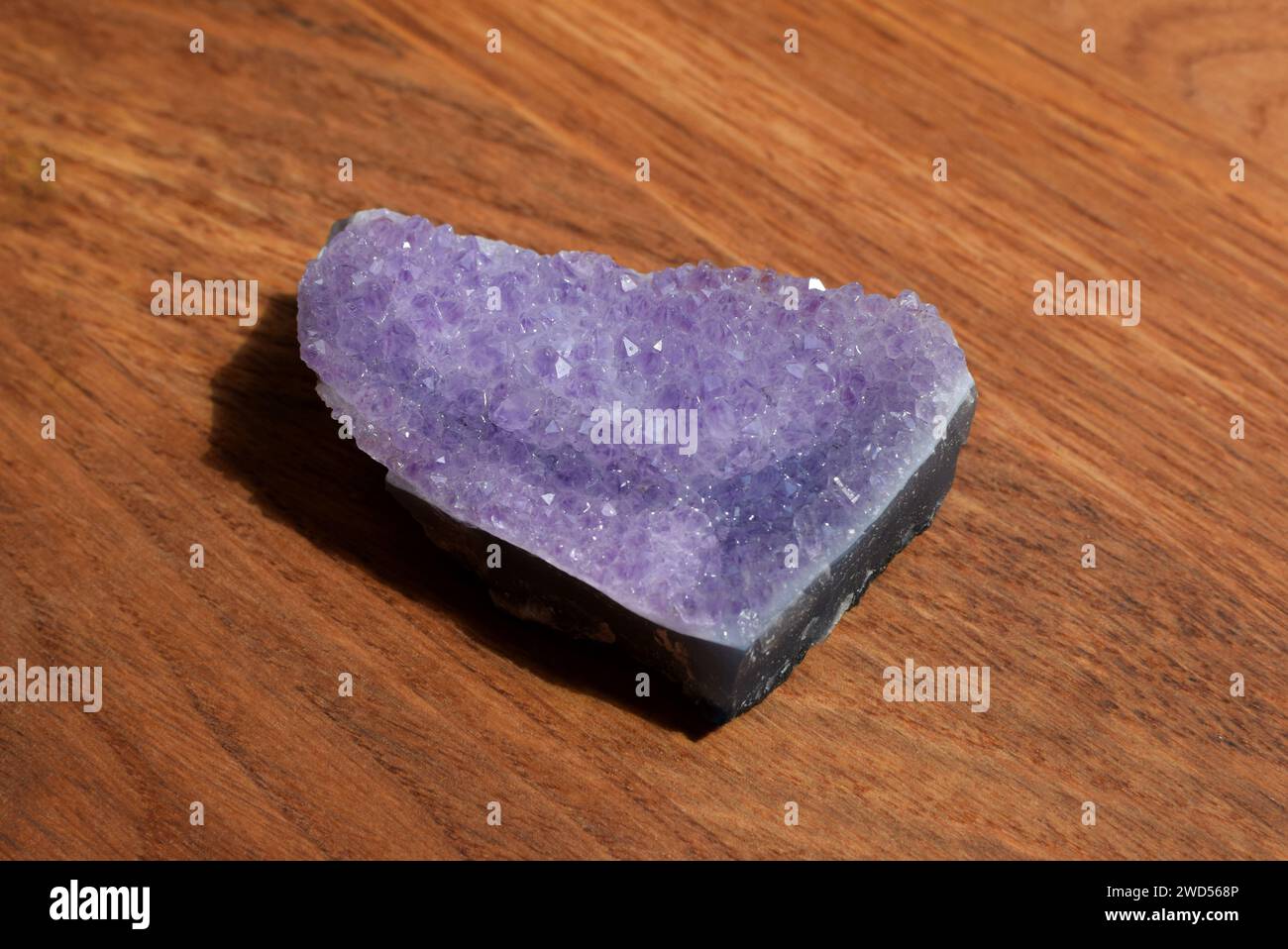 Schöne Fliedertrommel mit Amethyst-Kristallen auf hölzernem Hintergrund. Magische Halbedelsteine. Stockfoto