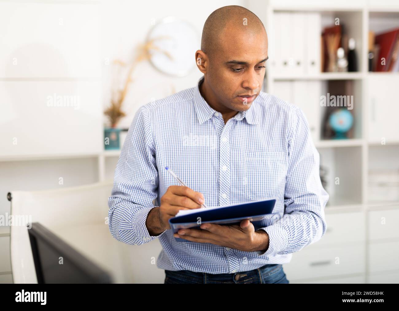 Geschäftsmann macht sich im Büro Notizen im Dokument Stockfoto