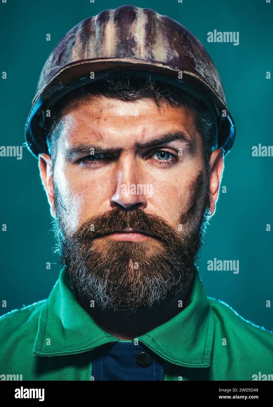 Nahaufnahmebild des Baumeisters in Bauhelm und Schutzanzug. Maschinenarbeiter oder Industriearbeiter mit Schutzhelm. Ernsthafter bärtiger Mann in Stockfoto