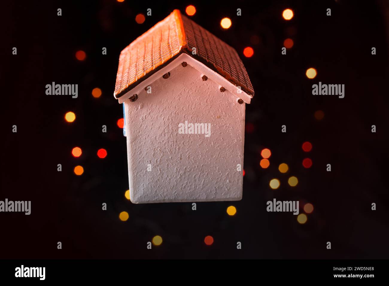 Kleines Modell Haus auf einem Bokeh ligh t einen dunklen Hintergrund Stockfoto