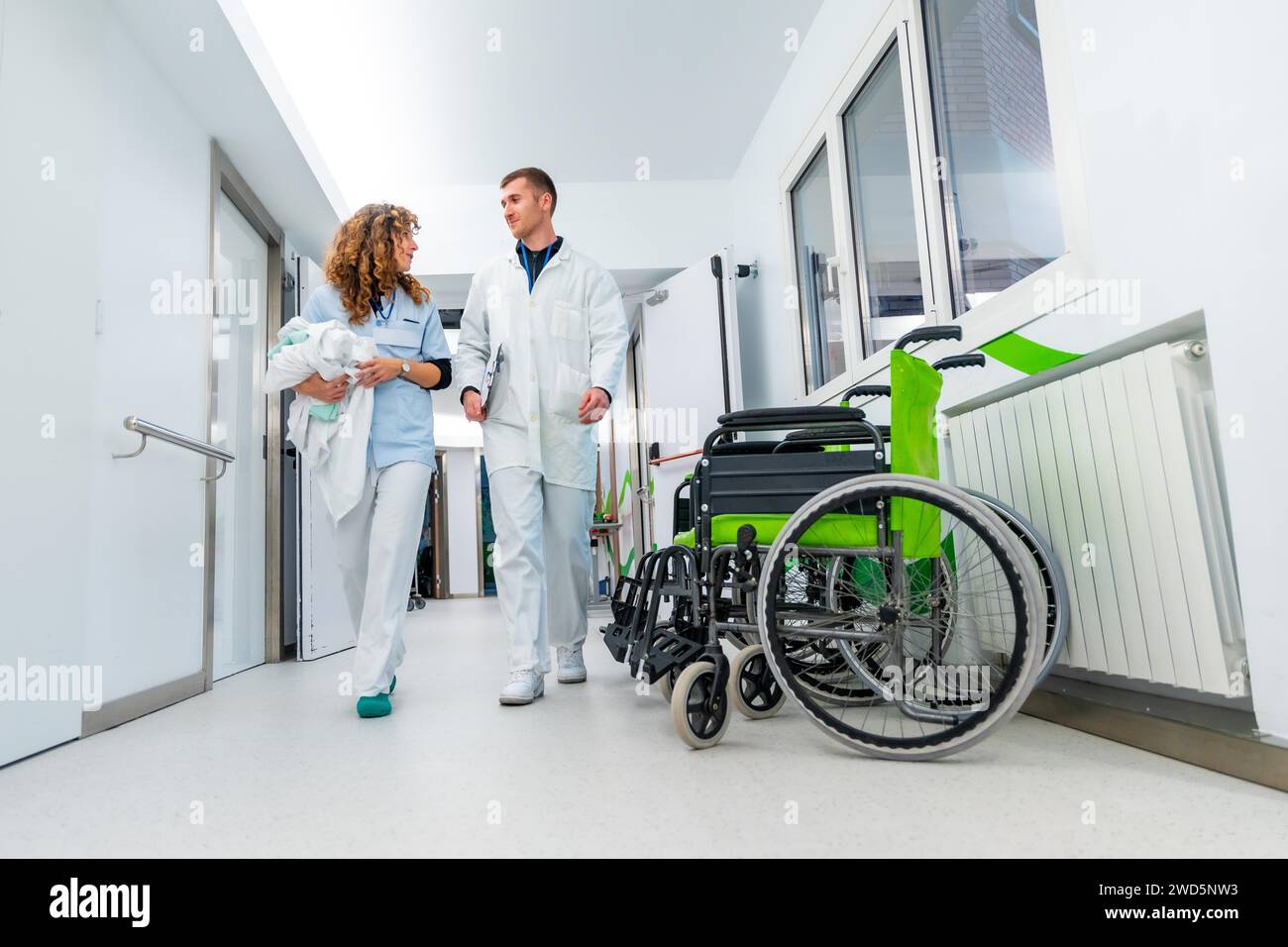 Niedrigwinkelansicht von Arzt und Krankenschwester, die mit Rollstühlen den Krankenhausflur entlang gehen Stockfoto