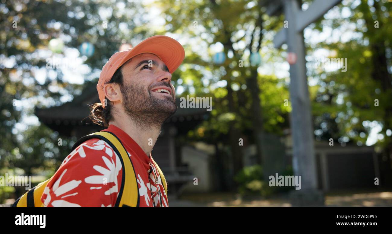 Outdoor, Denken und Mensch mit einem Lächeln, Reisen und Natur mit Sonnenschein, Japan und Tourismus. Person, Park und Mann mit Glück, Urlaub und Stockfoto