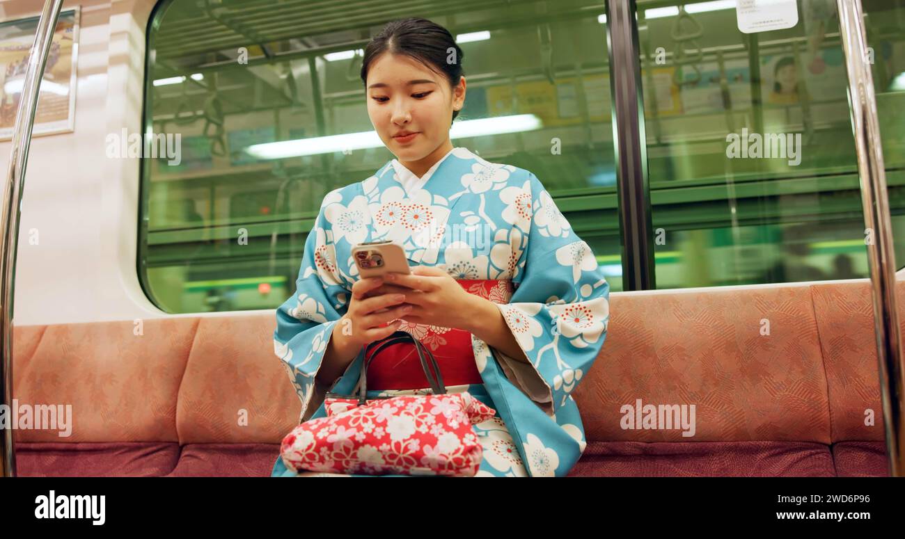 Frau, japan und Zug mit Kimono, Telefon und Reise mit öffentlichen Verkehrsmitteln, U-Bahn-Kugel in der Stadt. Person, Reise oder traditionelle Kleidung in Bewegung Stockfoto