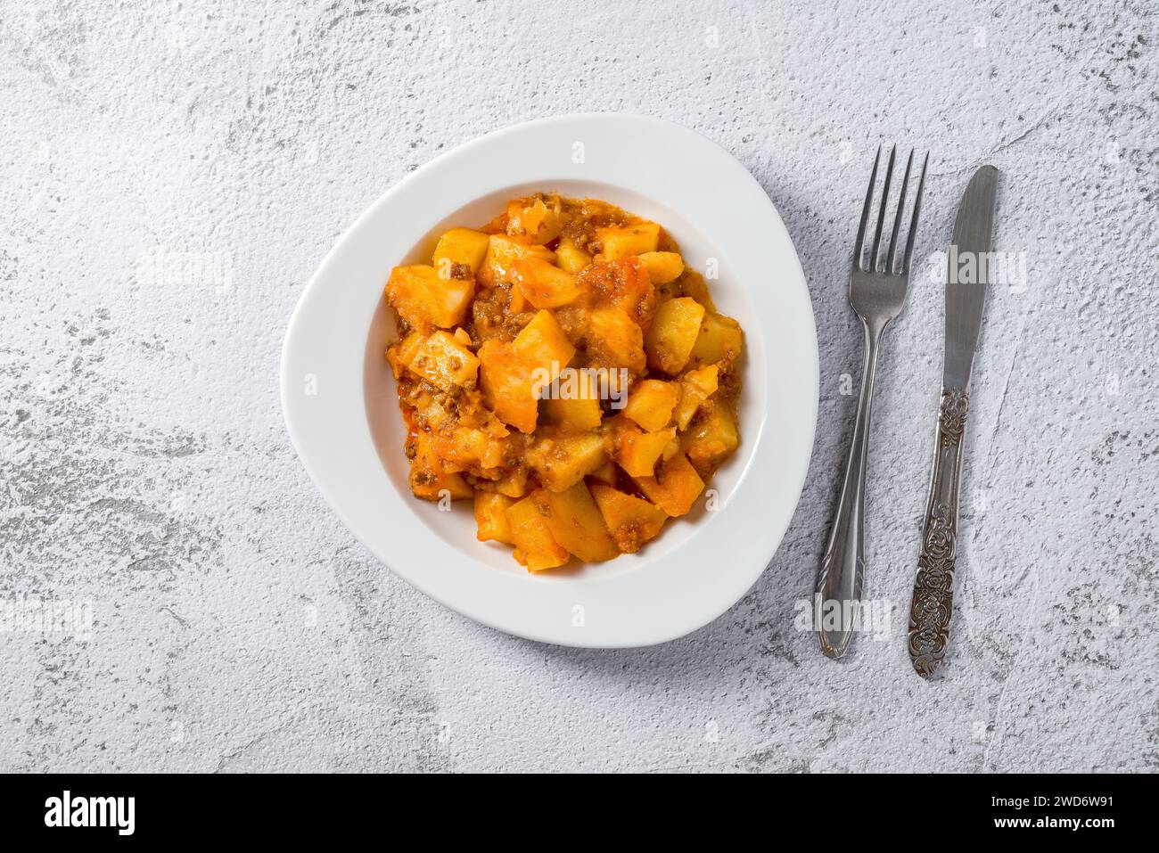 Hackfleisch und Kartoffelschale auf weißem Porzellanteller auf Steintisch Stockfoto