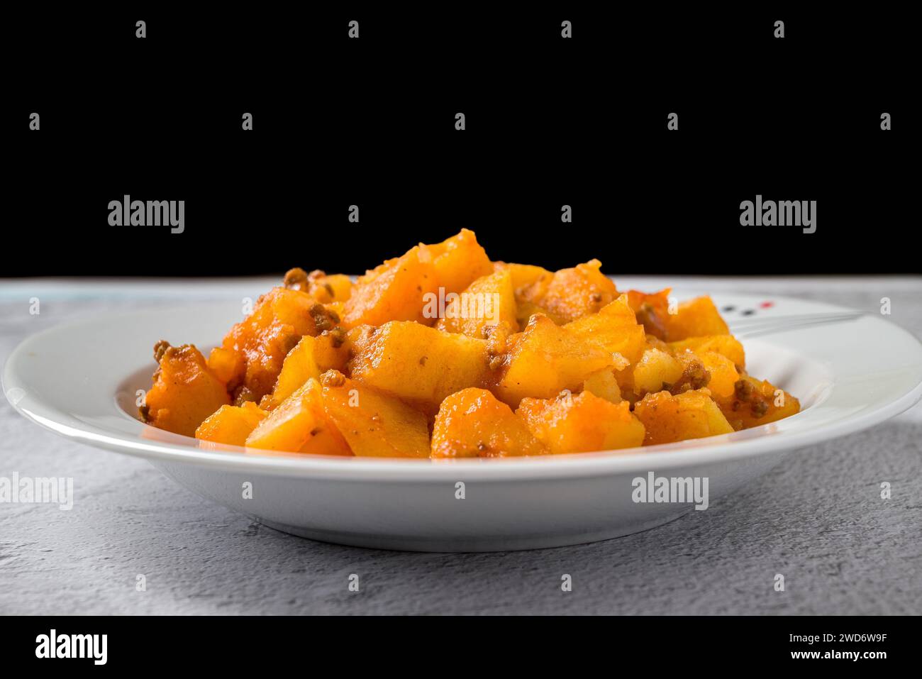 Hackfleisch und Kartoffelschale auf weißem Porzellanteller auf Steintisch Stockfoto