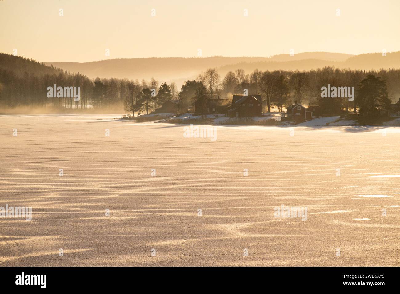 Häuser säumen das Ufer eines gefrorenen Sees in Grasmark, Schweden Stockfoto