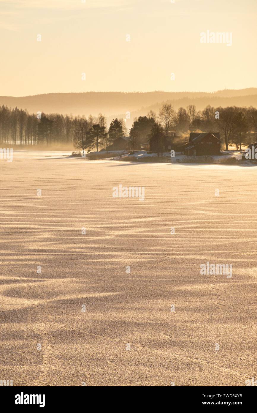 Häuser säumen das Ufer eines gefrorenen Sees in Grasmark, Schweden Stockfoto