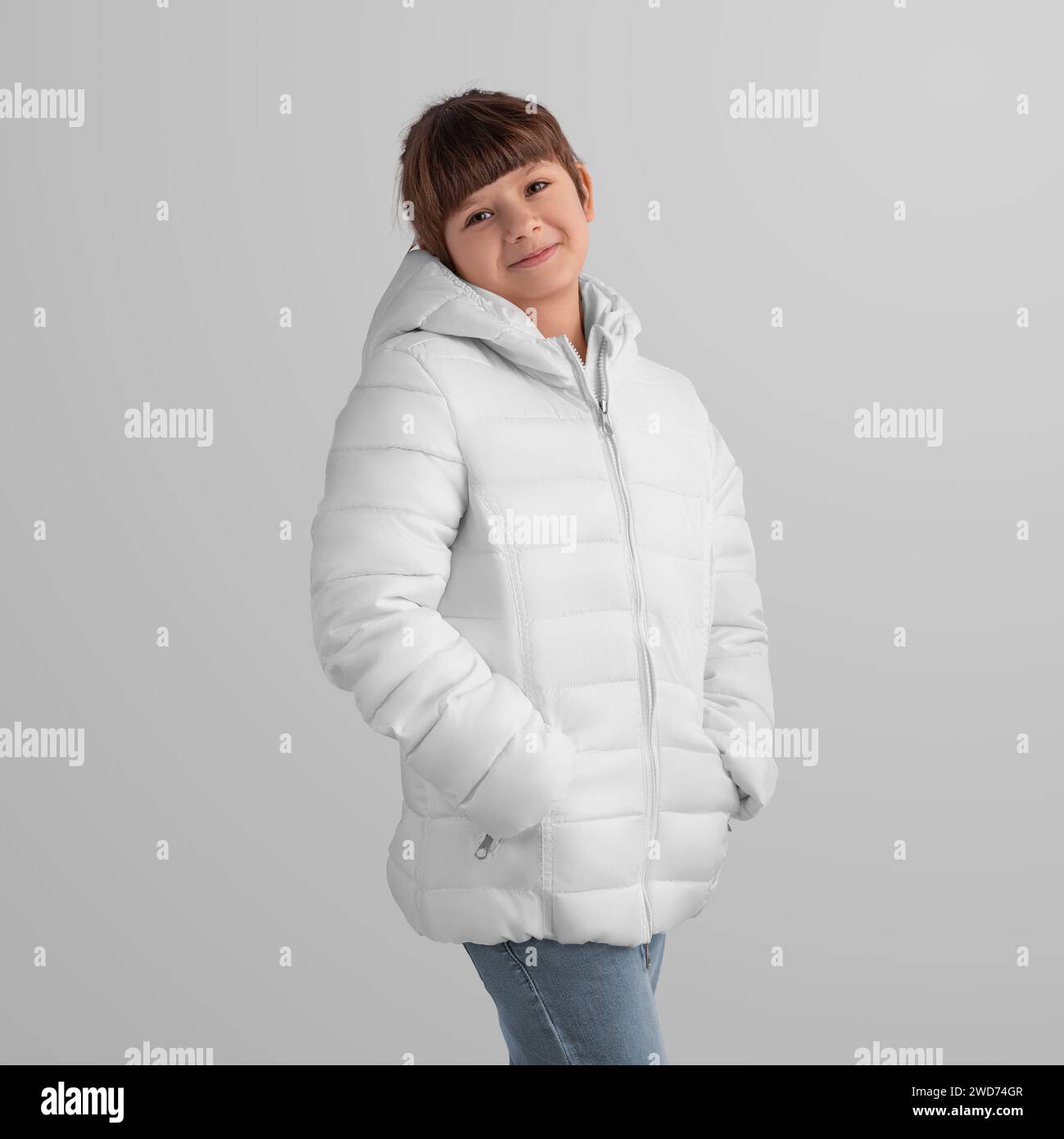 Mädchen in einer schicken weißen Winterjacke - Oberbekleidung Vorlage für Werbung. Elegantes Design für den kommerziellen Einsatz. Mockup von warmen Klamotten an einem Kind in Jeans Stockfoto