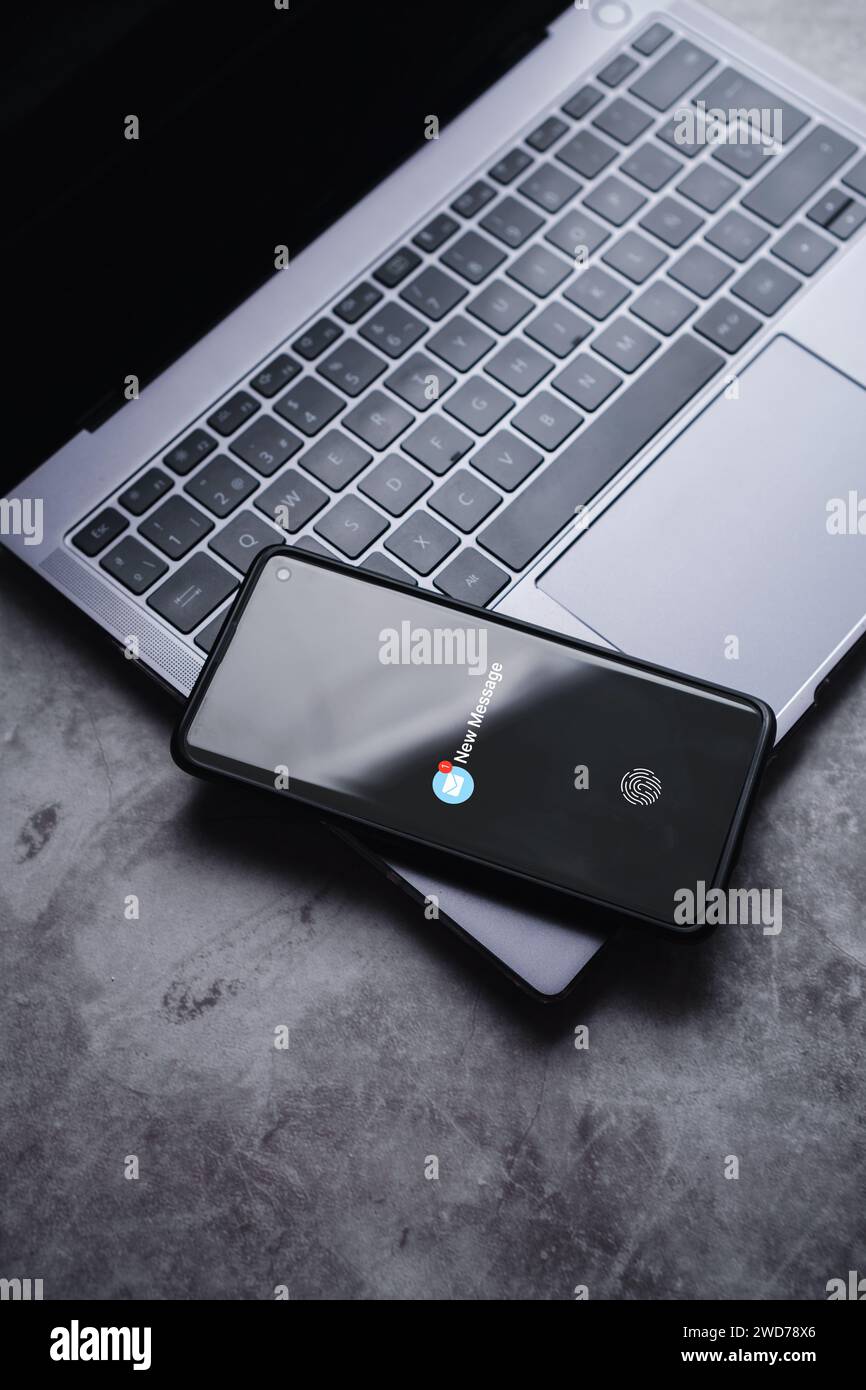 Smartphone auf dem Laptop mit einer neuen Benachrichtigung auf dem Bildschirm. Kommunikationstechnologie für Unternehmen. Inbox-Ansicht. Neue E-Mail auf dem mobilen Smartphone Stockfoto