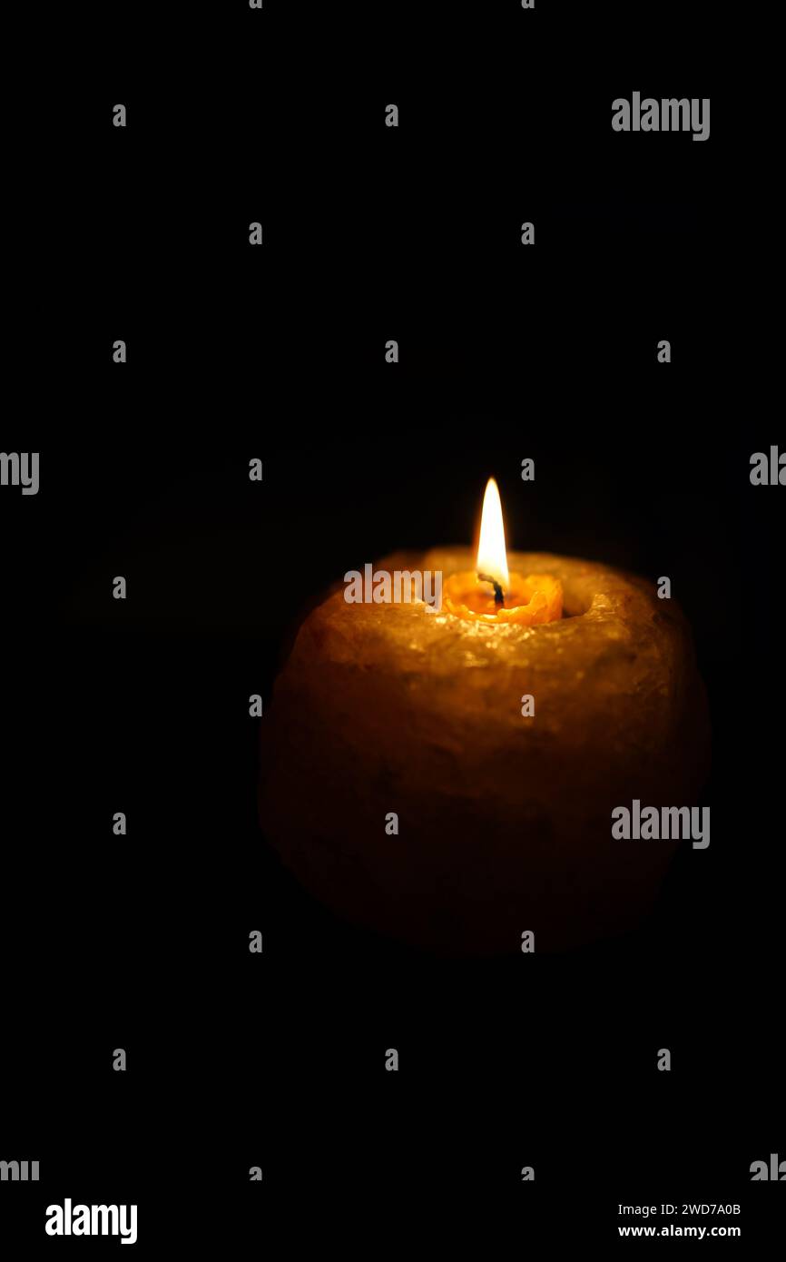 Eine vertikale Kerze in der Dunkelheit Stockfoto