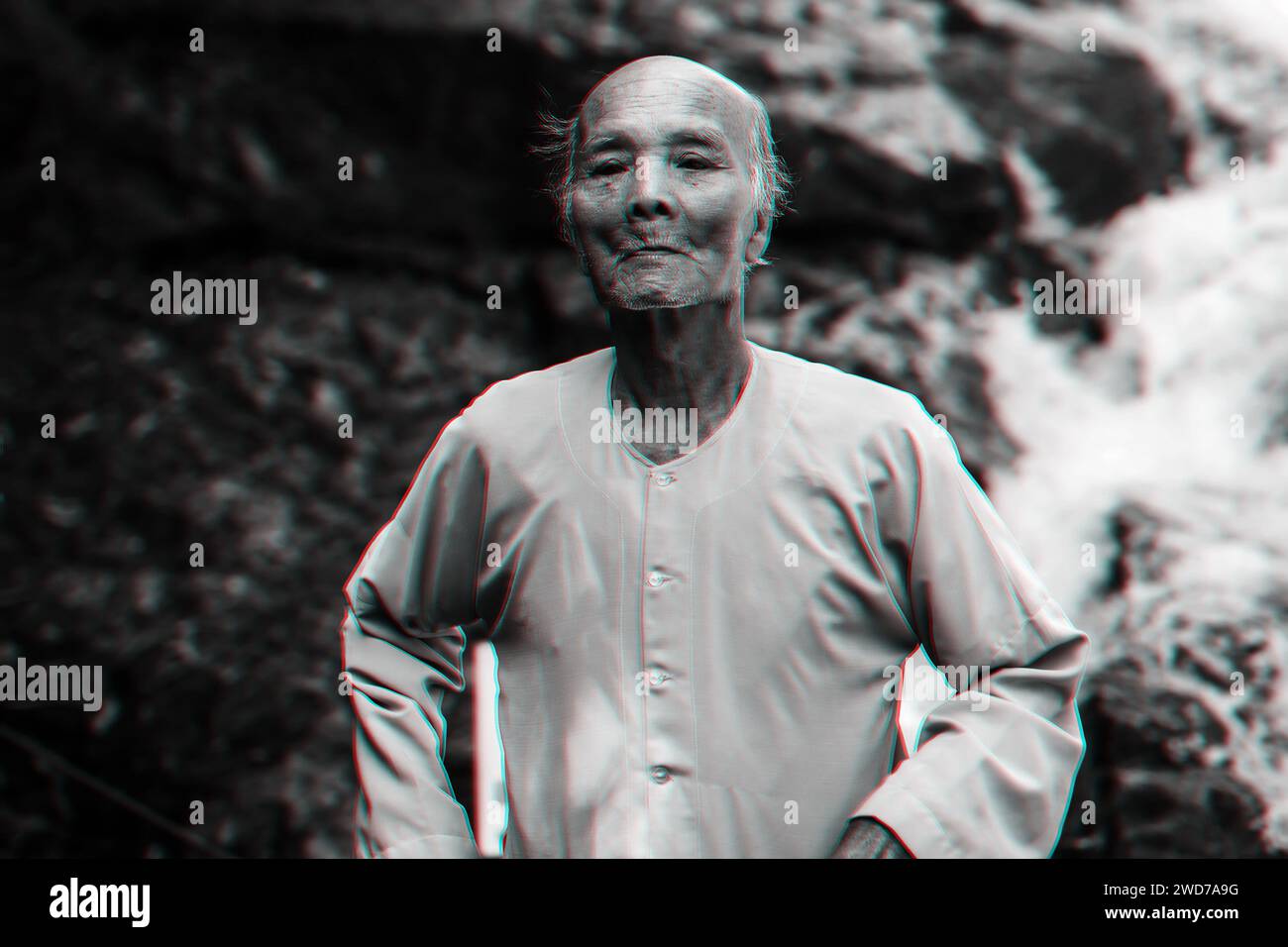 Porträt eines älteren vietnamesischen Achtzigärs im Park. Authentischer asiatischer Großvater Langleber. Schwarzweißfoto mit 3D-Glitcheffekt Stockfoto