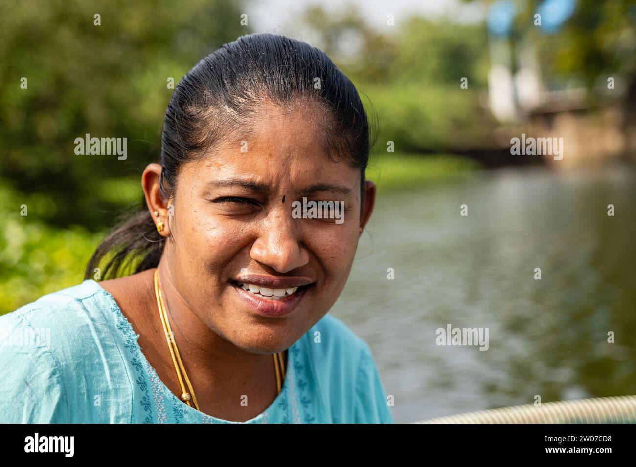 Eine sonnenverwöhnte Frau, die Augen funkeln vor Freiheit, navigiert mit ihrem kleinen Segelboot durch die Gegend Stockfoto