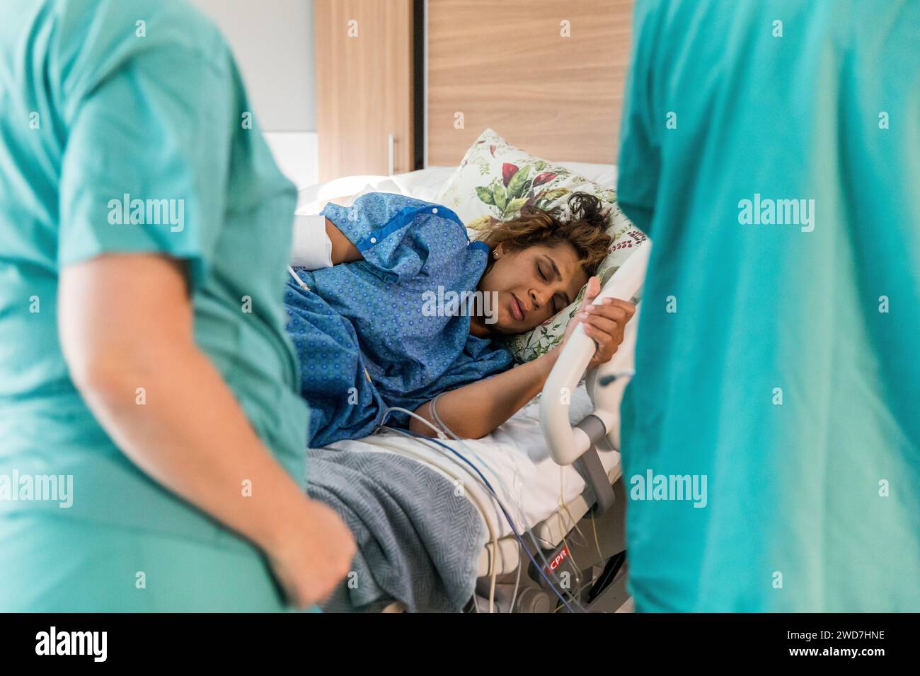 Indische Mutter liegt im Krankenhausbett und greift Geländer Stockfoto