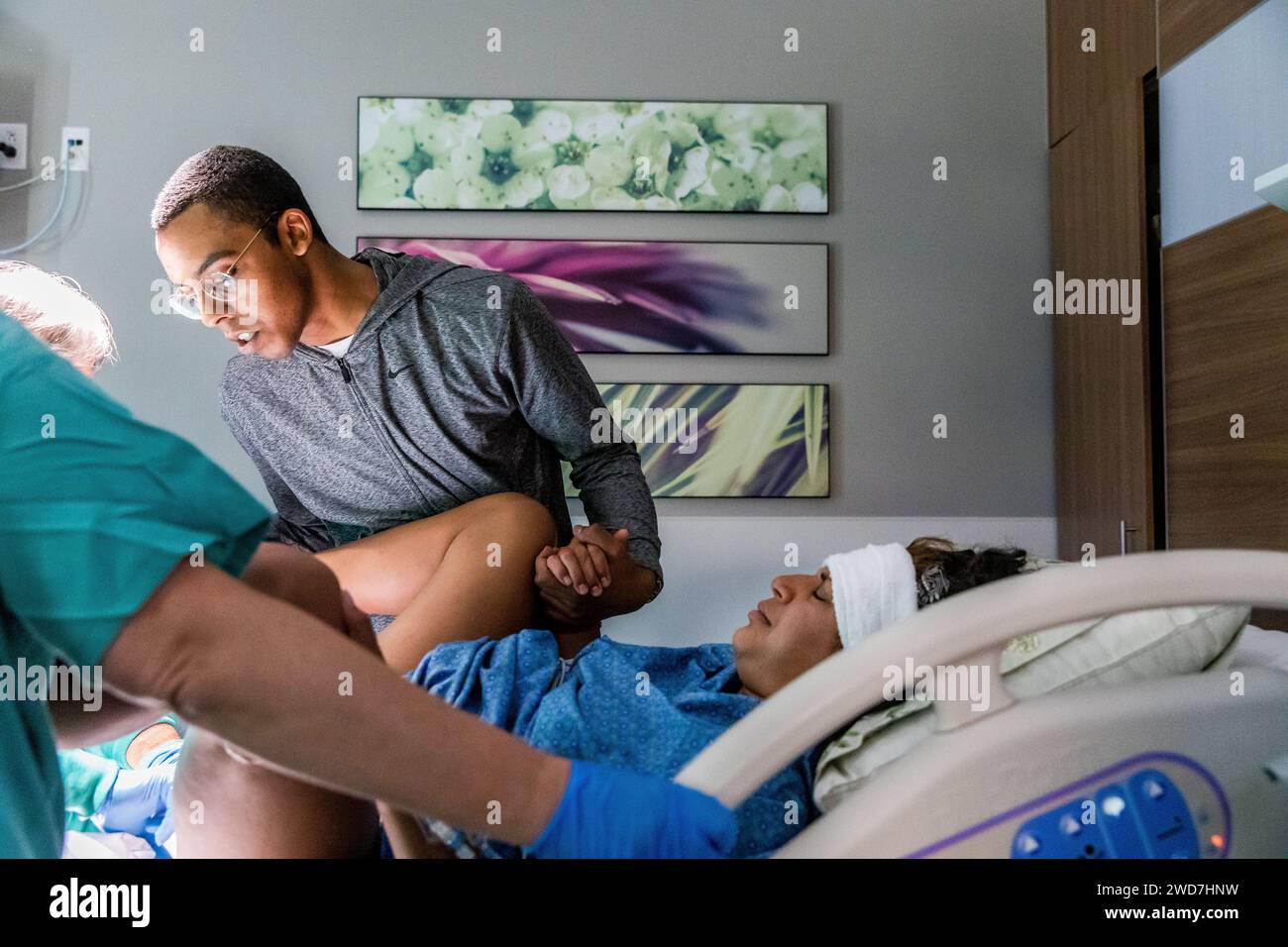 Vater überprüft das Baby zwischen den Wehen bei der Geburt im Krankenhaus Stockfoto