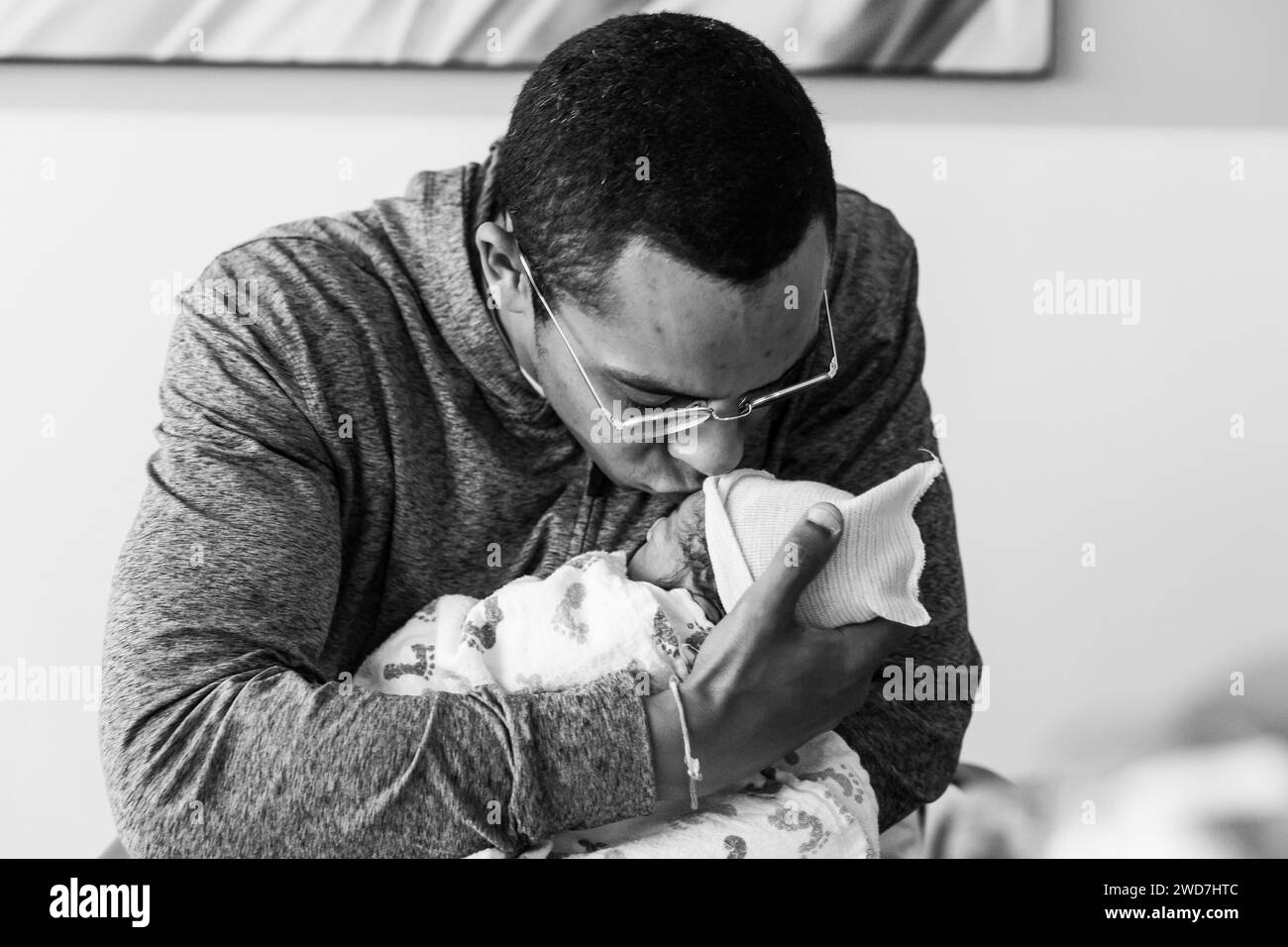 Afroamerikaner hält das Neugeborene zum ersten Mal fest und küsst es Stockfoto