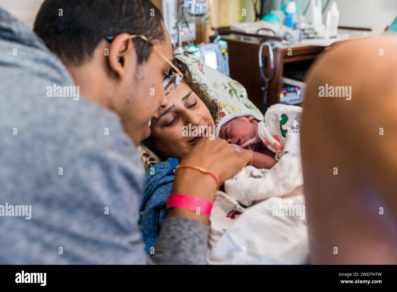 Multirassisches Paar lächelt Neugeborenes nach Krankenhausgeburt an Stockfoto