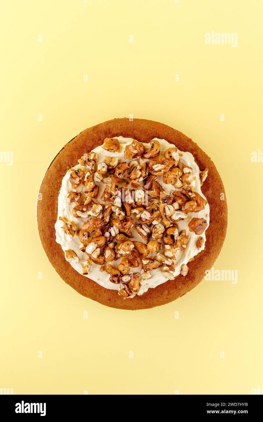 Biskuitkuchen mit Sahne und Nüssen auf gelbem Hintergrund Stockfoto