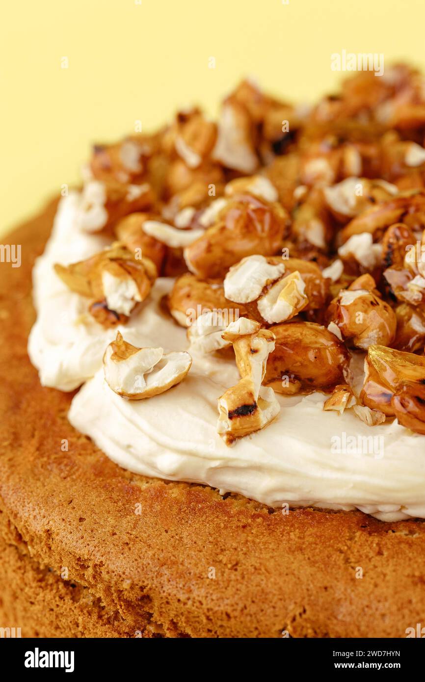 Biskuitkuchen mit Sahne und Nüssen auf gelbem Hintergrund Stockfoto