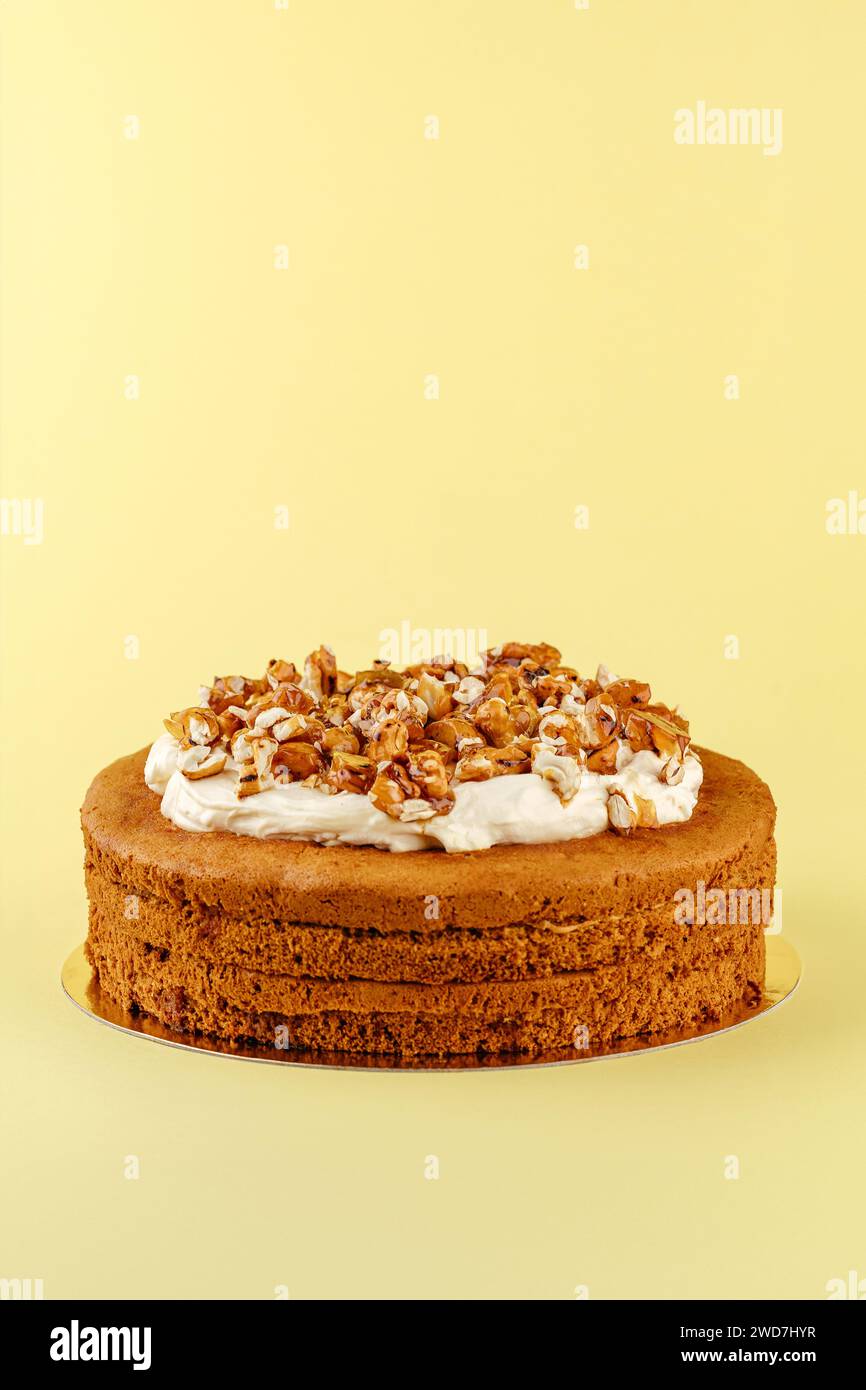 Biskuitkuchen mit Sahne und Nüssen auf gelbem Hintergrund Stockfoto