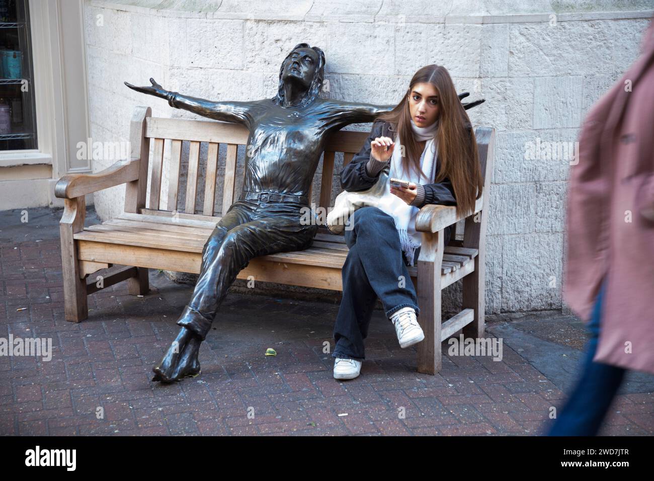 Weibliche Besucherin der Carnaby Street „in Conversation“ mit John Lennon Statue „Imagine“ von Bildhauer Lawrence Holofcener. London. UK. (137) Stockfoto