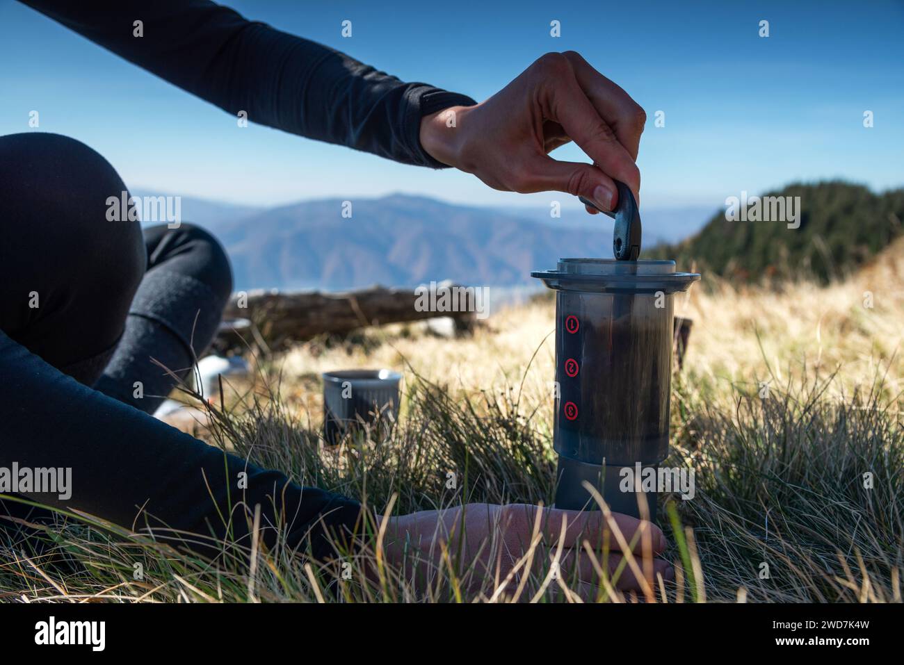 Close Up Female Hands bereitet Kaffee mit einer AeroPress in den Bergen zu Stockfoto