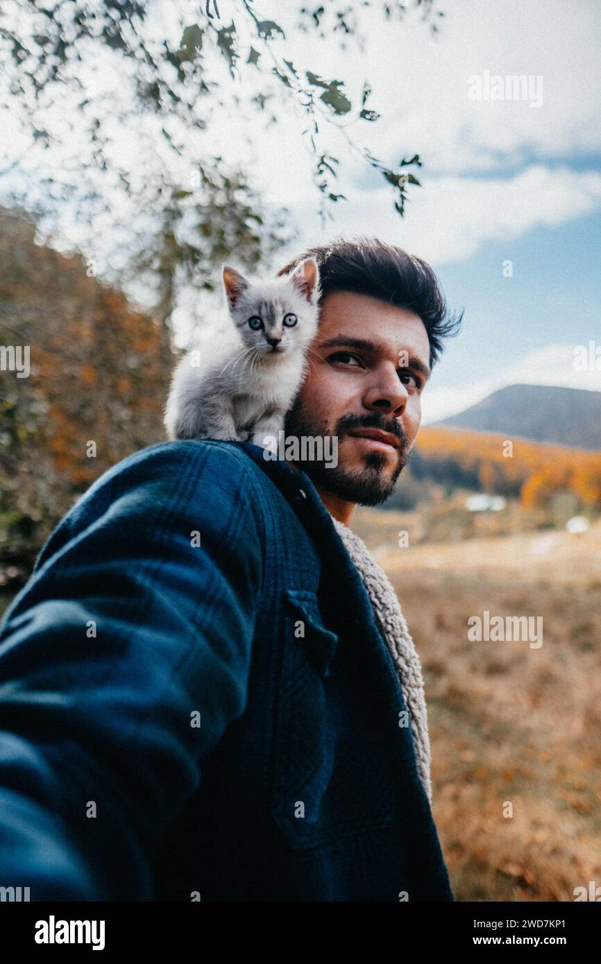 Winziges Kätzchen, das in der Natur auf der Schulter des Mannes sitzt Stockfoto