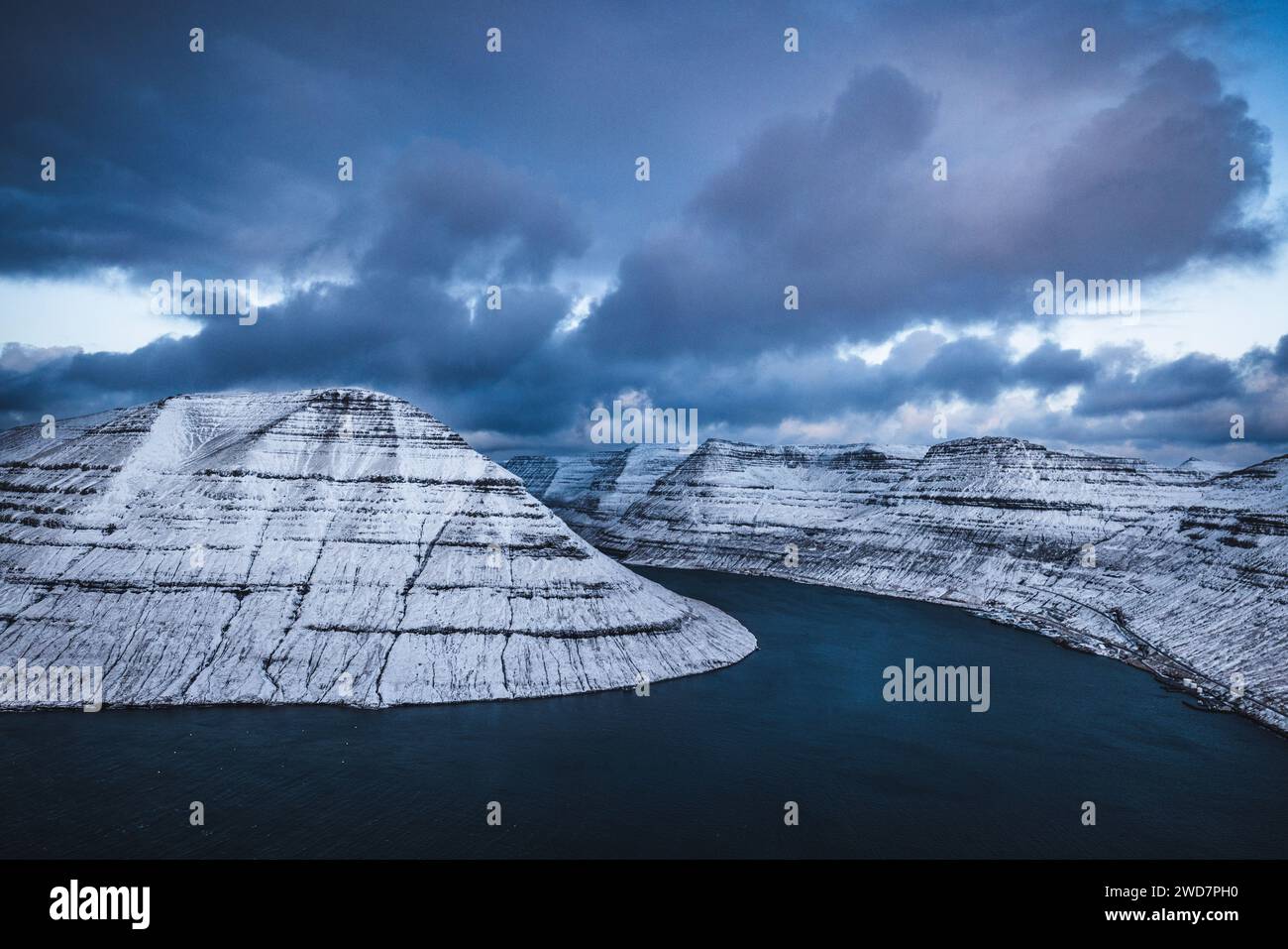 Blick auf schneebedeckte Berge und Wolken, die über einem Fjord thronen Stockfoto