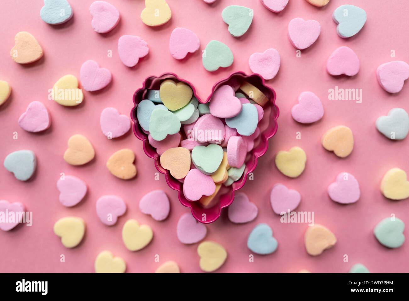 Flache Lage eines Haufen Süßwarenherzen vor rosa Hintergrund Stockfoto