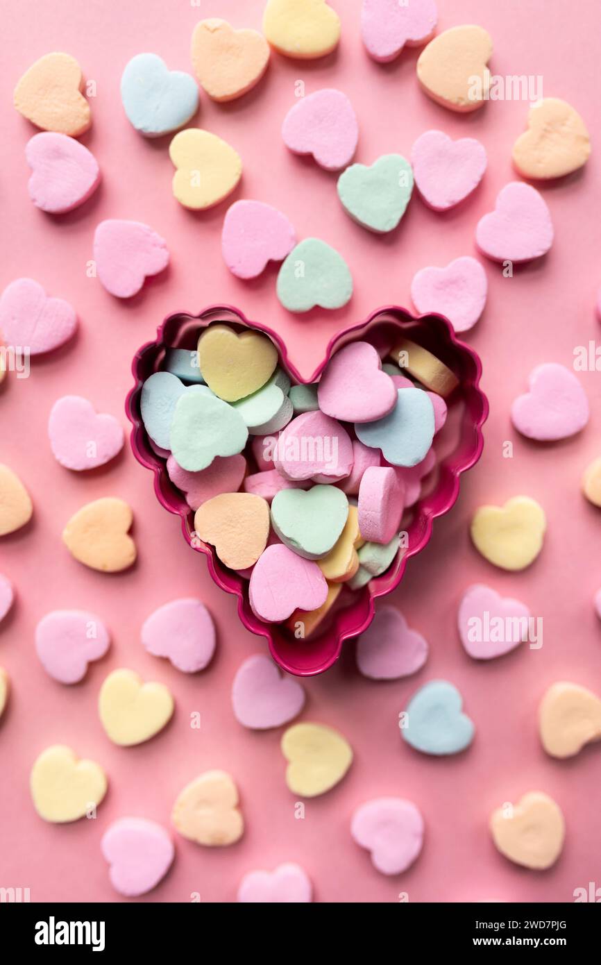 Flache Lage eines Haufen Süßwarenherzen vor rosa Hintergrund Stockfoto