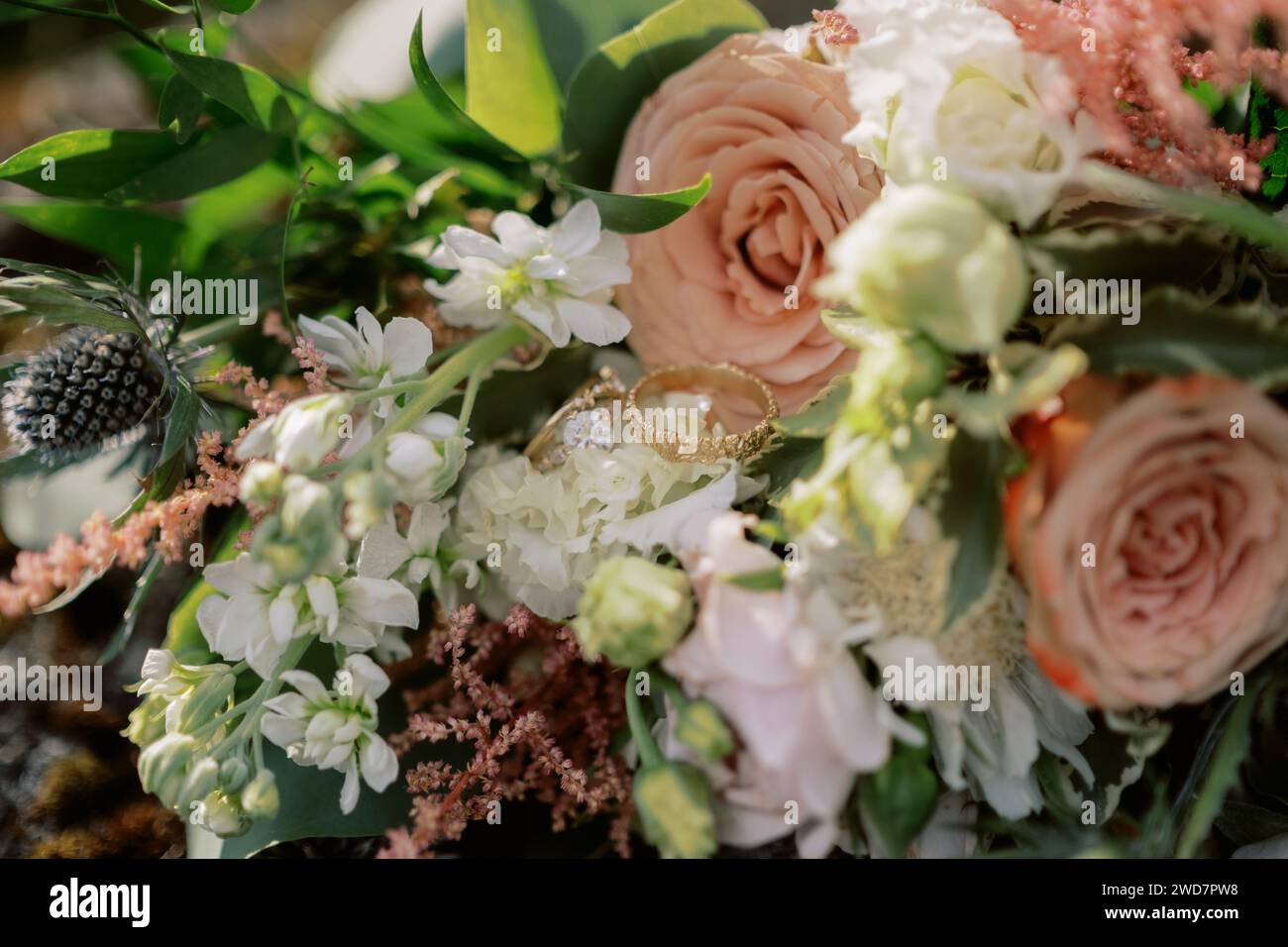 Goldene Ringe für Braut und Bräutigam, eingebettet in Blumenstrauß Stockfoto