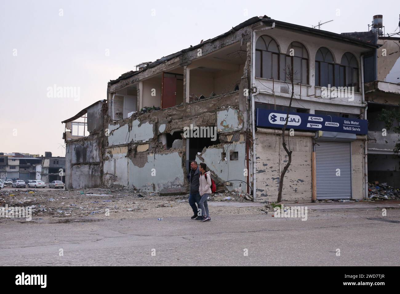 Antakya, T¨¹rkiye. Januar 2024. Menschen gehen an beschädigten Gebäuden in Antakya, T¨¹rkiye, am 18. Januar 2024 vorbei. Antakya wurde Anfang Februar letzten Jahres von verheerenden Erdbeben heimgesucht und befindet sich derzeit im Wiederaufbau. Quelle: Li Zhenbei/Xinhua/Alamy Live News Stockfoto