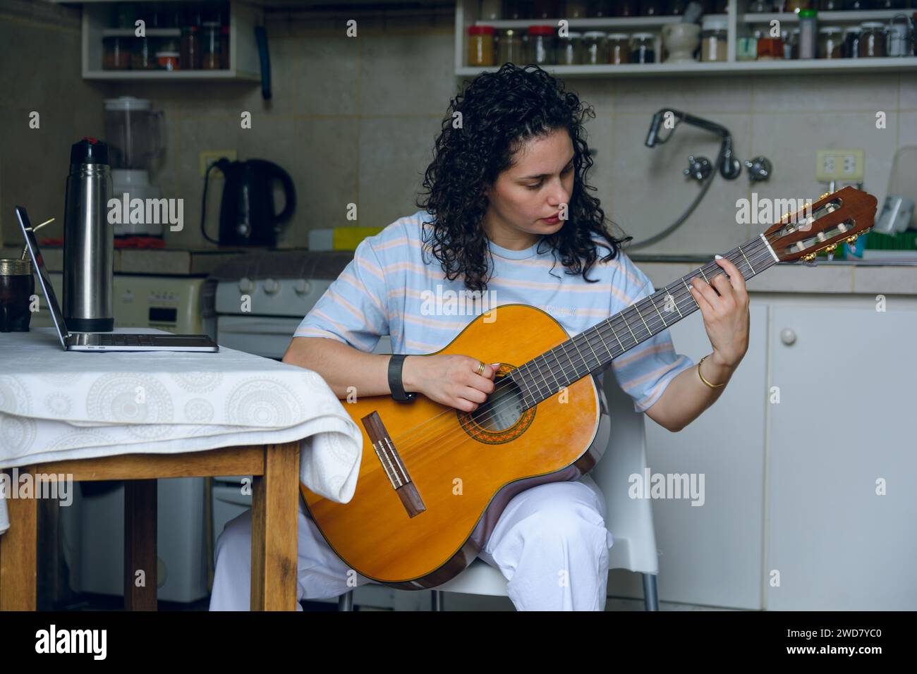 Vorderansicht junge lateinfrau, die sich zu Hause im Sitzen konzentriert und ihr neues Lied auf Akustikgitarre übt, ihre musikalische Technik mit korrekter Haltung einstudiert Stockfoto