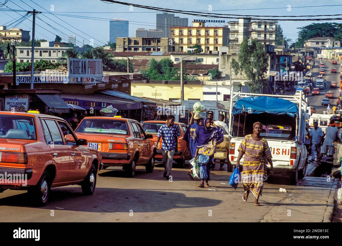Elfenbeinküste, Abidjan; Überblick über eine geschäftige Straße der Stadt mit Taxis und Fußgängern. Stockfoto