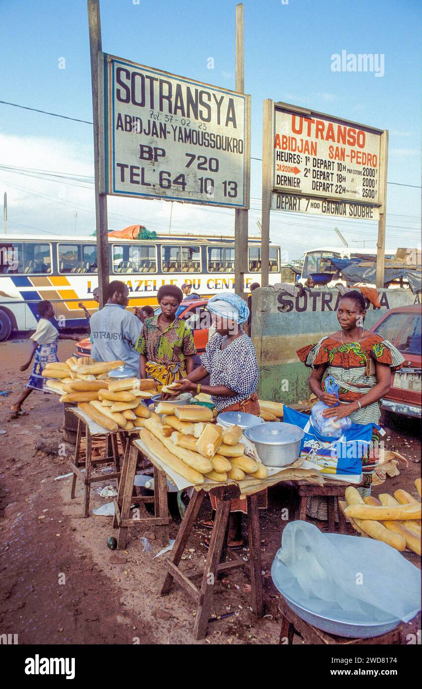 Elfenbeinküste, Abidjan; Frauen verkaufen französisches Brot unter Schild mit Fahrplan für Busse. Stockfoto