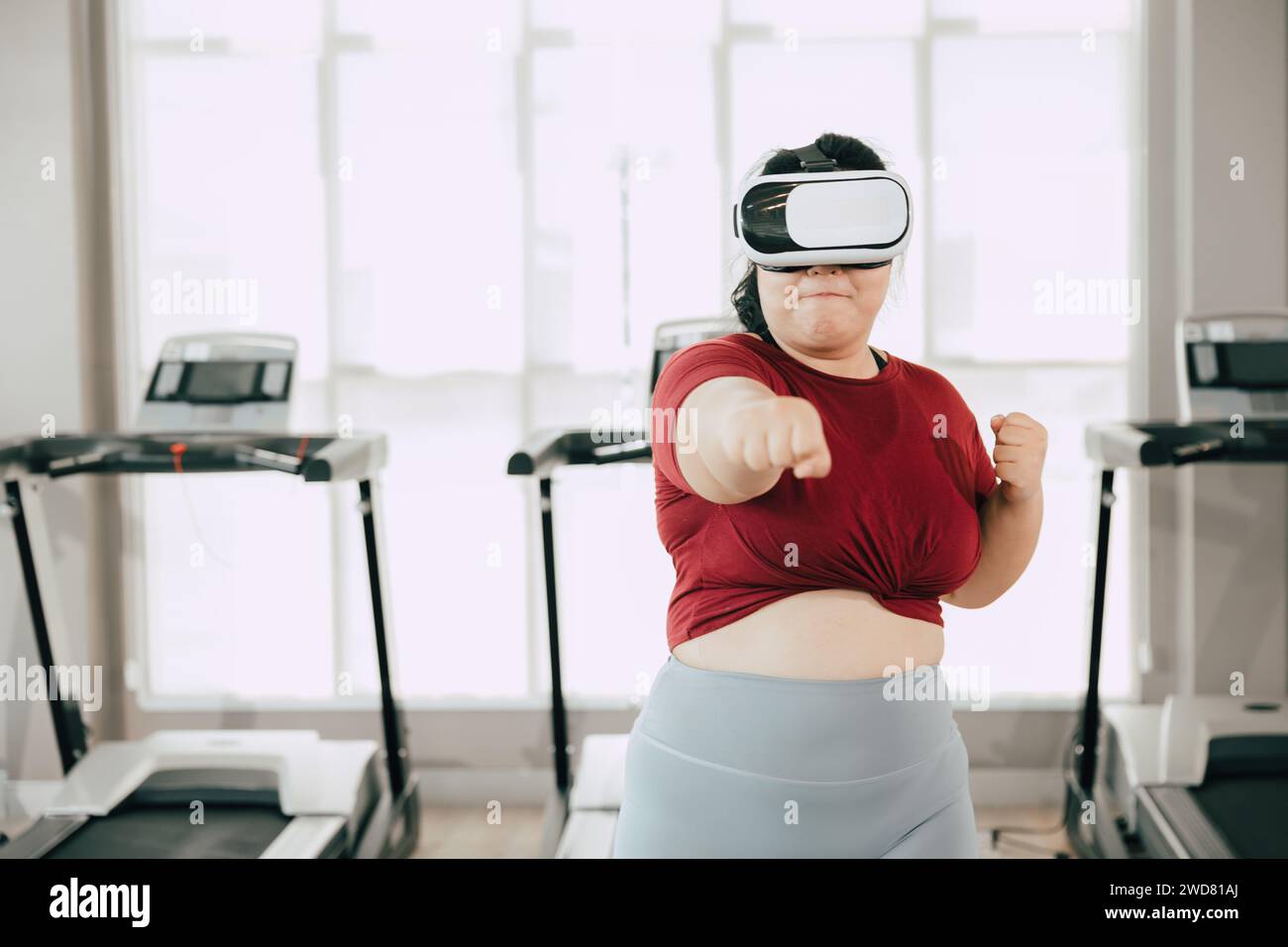 Fette Frauen mit VR-Headset spielen visuelles Reality-Sportspiel für Sport. Menschen, die moderne Technik für das Heilbehandlungskonzept nutzen. Stockfoto