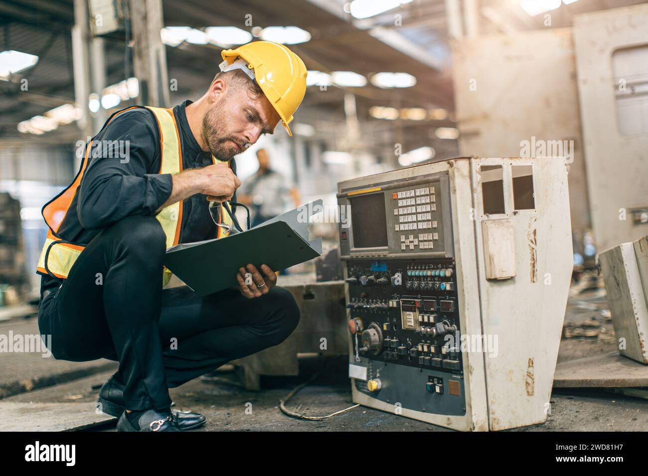 Junger Ingenieur männlich Prüfung Maschinenteile Service Reparatur. Maschinenarbeiter in einer Fabrik der Schwerindustrie, die alte Maschine überprüft Stockfoto