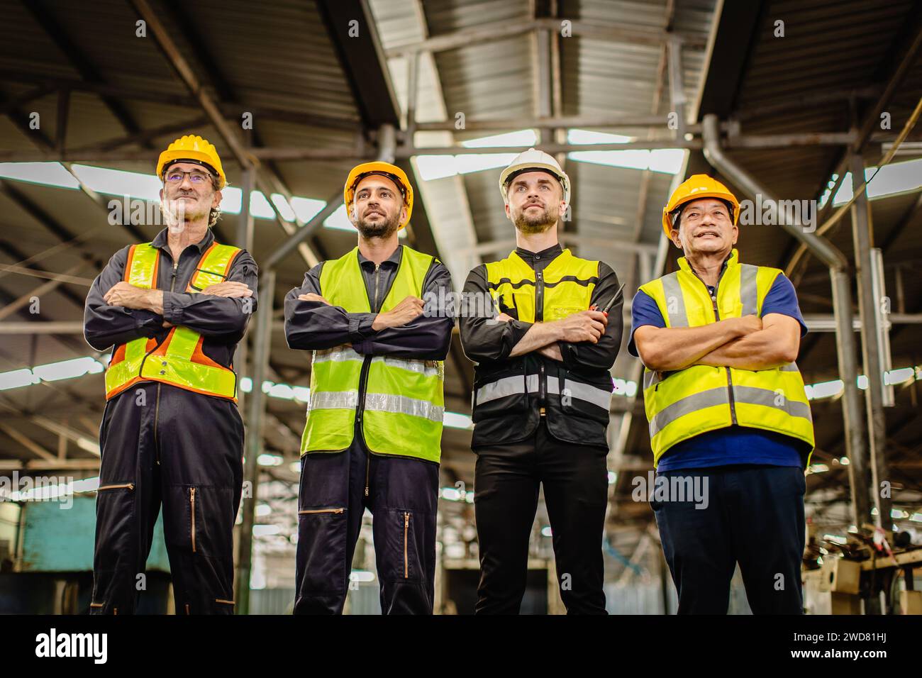Ein männliches Ingenieurteam, das in der Schwerindustrie arbeitet, steht zusammen. Eine Gruppe professioneller Mitarbeiter arbeitet glücklich und selbstbewusst zusammen. Stockfoto