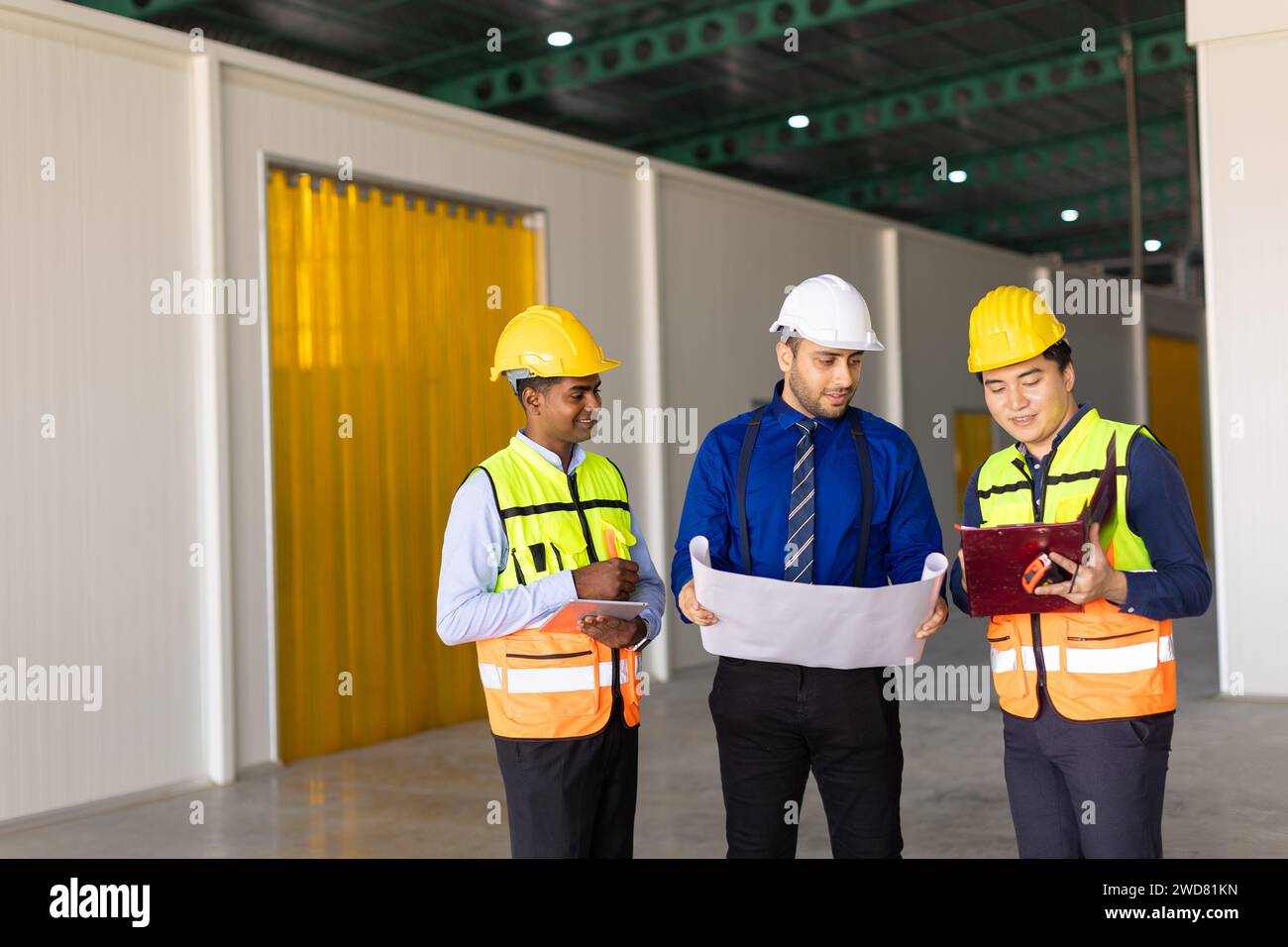 Das Team der Ingenieure, das mit der Arbeit des Architekten arbeitet, inspiziert das Bauprojekt der großen Gebäudefabrik mit Grundriss Stockfoto