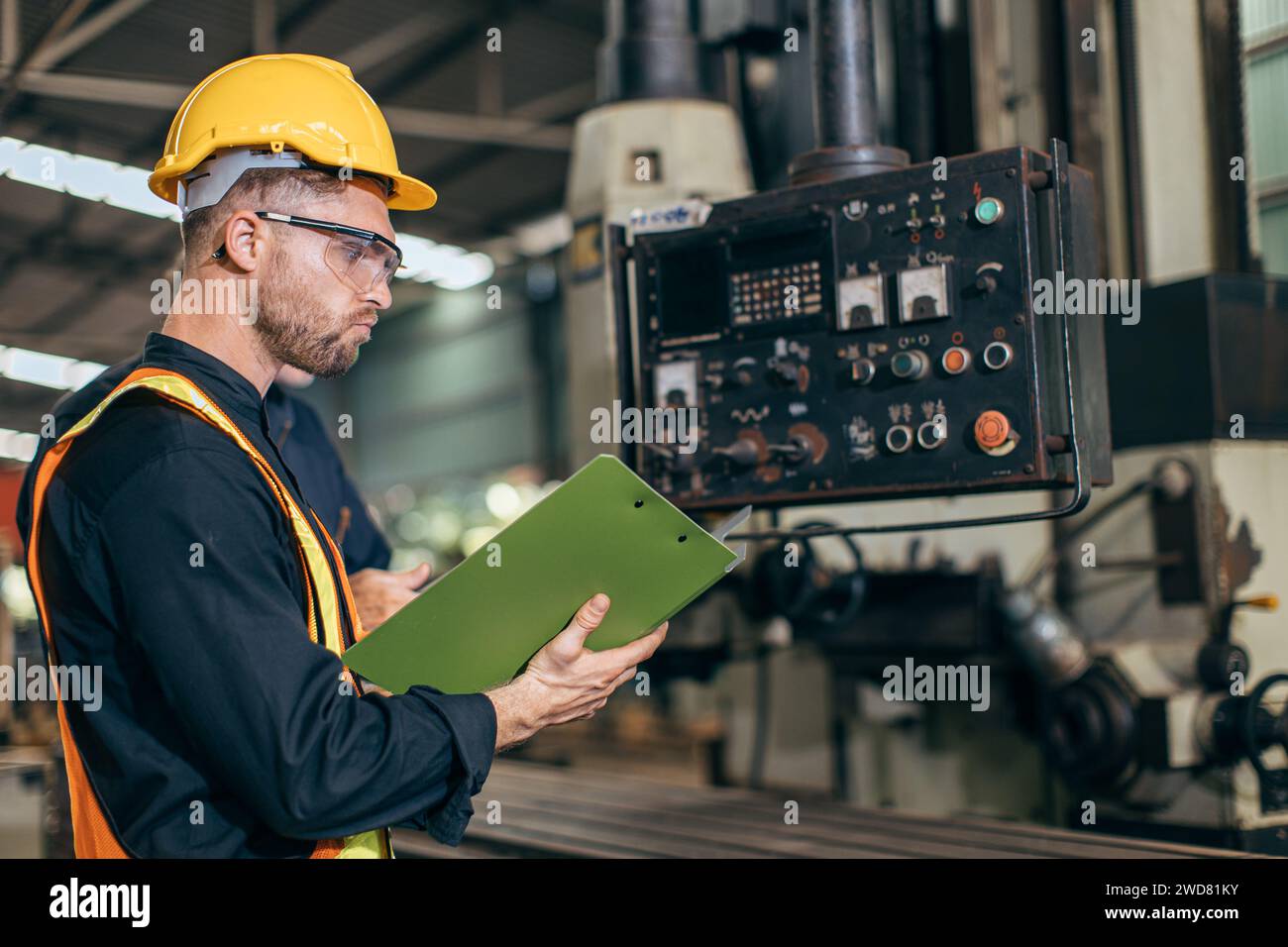 Professioneller Ingenieur, der das Lesen der Bedienungsanleitung steuert, bedienen Sie das Programm CNC-Fräsmaschine in der Schwerindustriefabrik Stockfoto