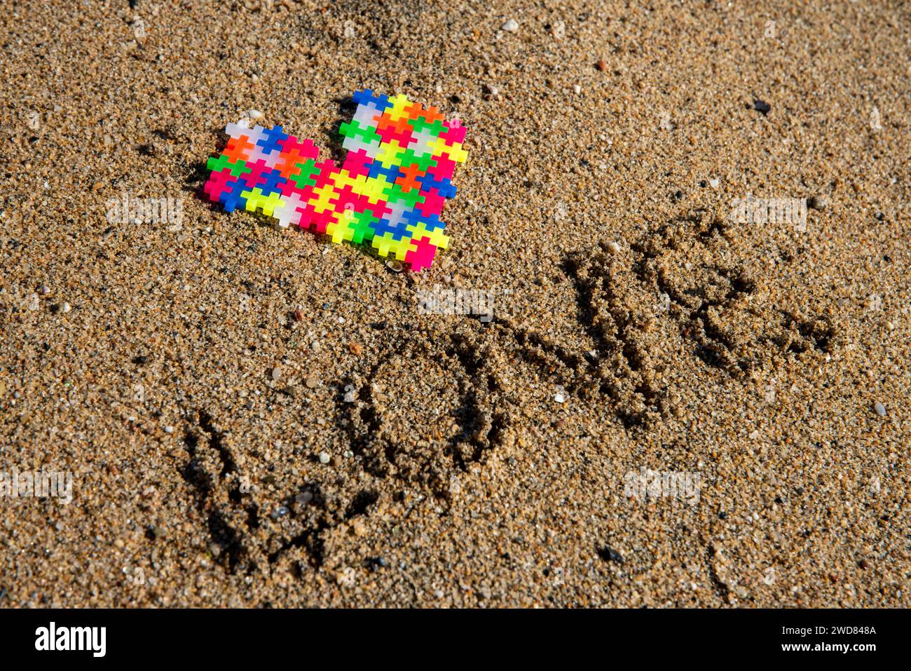 Puzzle Liebe am Ufer: Lebendiges Herz entsteht aus sandiger Hingabe, einer farbenfrohen Valentinstag-Symphonie. Stockfoto