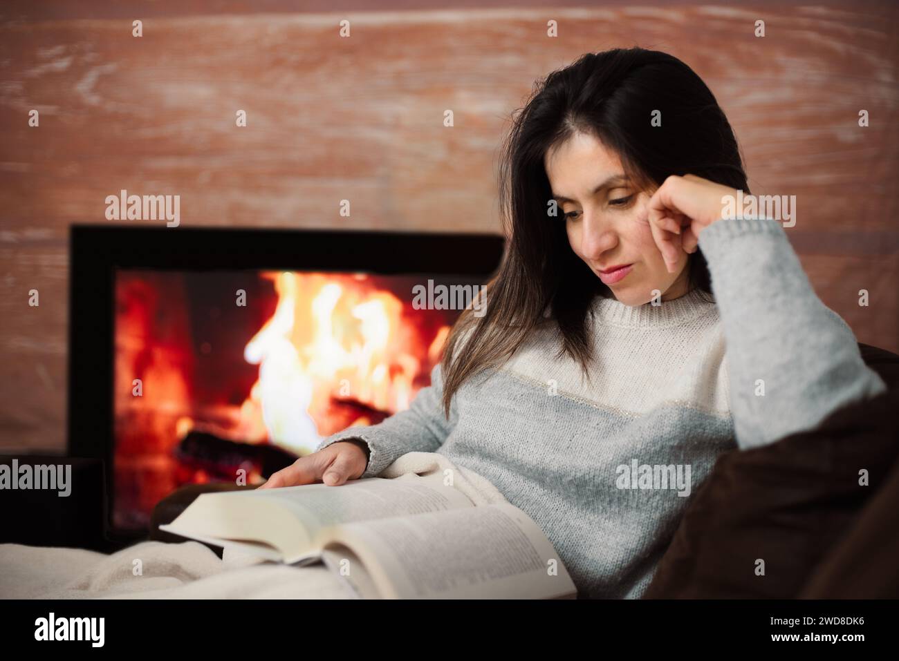 Die Frau liest gern ein Buch von ihrem Sofa zu Hause. Stockfoto